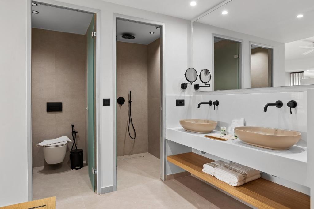 Mūsdienīgs vannas istabas interjers ar divām izlietnēm, dušu un tualeti. Eleganta dizaina elementi un funkcionālas iekārtas rada komfortablu atmosfēru.
