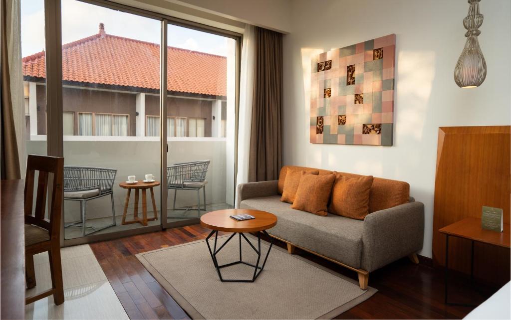 Mūsdienīga viesnīcas viesistaba ar dīvānu, kafijas galdiņu un balkonu, kas piedāvā skatu uz āru. Interjera dizains ir elegants un ērts, ar siltām krāsām un dabīgiem materiāliem.