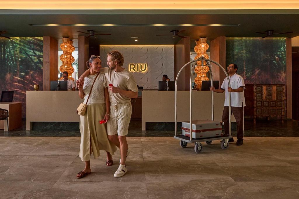 Pāris ienāk viesnīcā RIU Turquoise Mauritius ar koferiem.