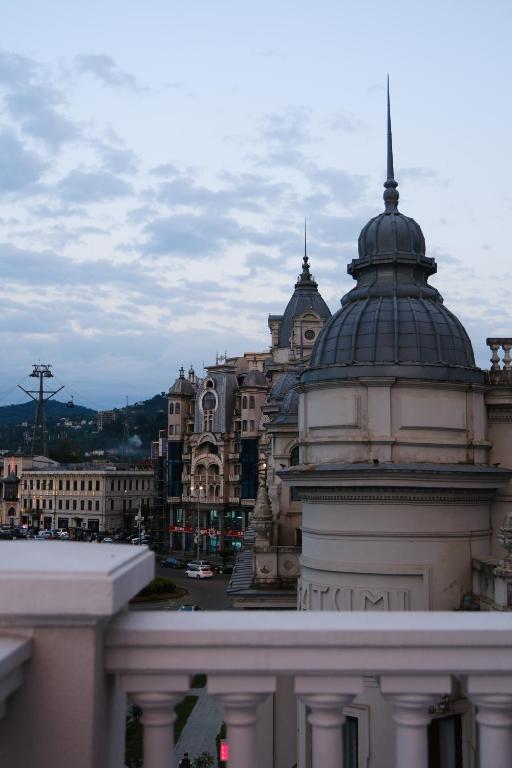 Pilsētas ainava ar vēsturiskām ēkām un skatu uz kalniem, kas redzami fona daļā, pievērš uzmanību arhitektūras detaļām.