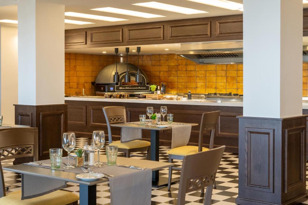 Mūsdienīgs restorāna interjers ar elegantām galdiem un krēsliem, atvērta virtuve un liela krāsaina krāsns. Ideāls vieta, kur baudīt gardas maltītes.