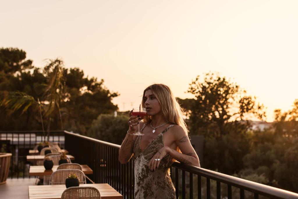 Sieviete ar kokteili, baudot saulrietu pie Cook's Club Ialysos Rhodes