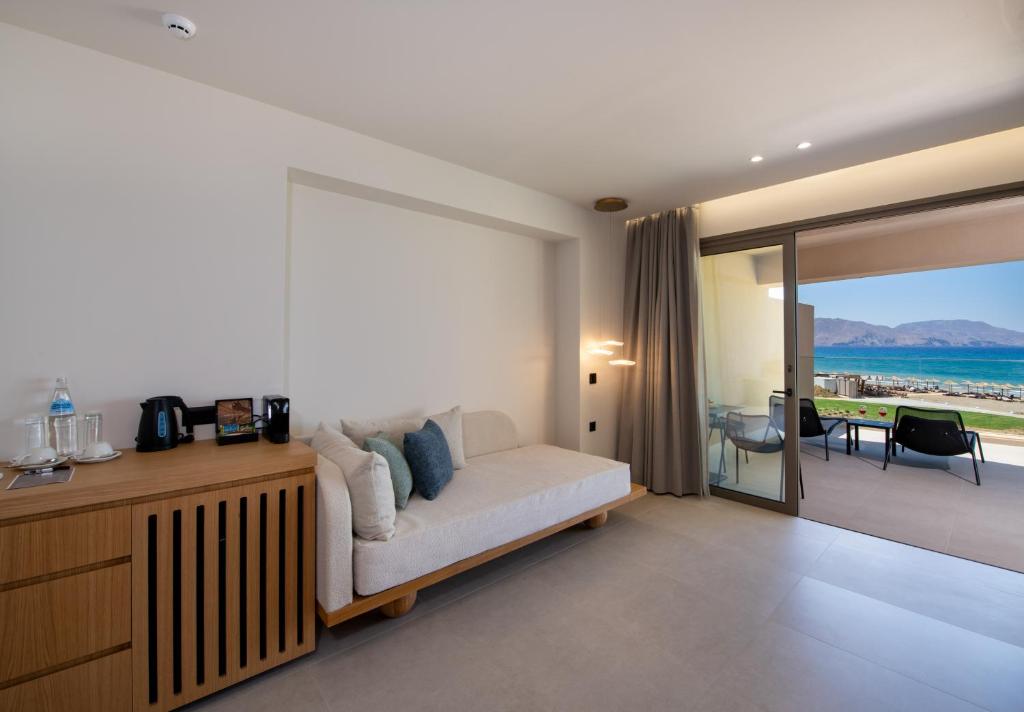 Mūsdienīgs viesnīcas numurs ar skatu uz jūru, ieskaitot dīvānu, koka mēbeles un terasi. Elegantā interjera dizains rada mierīgu atmosfēru.
