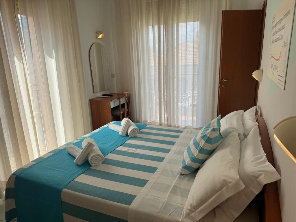 Mūsdienīga guļamistaba ar gaišiem aizkariem, divguļamo gultu un rakstāmgaldu. Istabā ir pieejami baltie dvieļi un spilveni ar horizontālām svītrām.