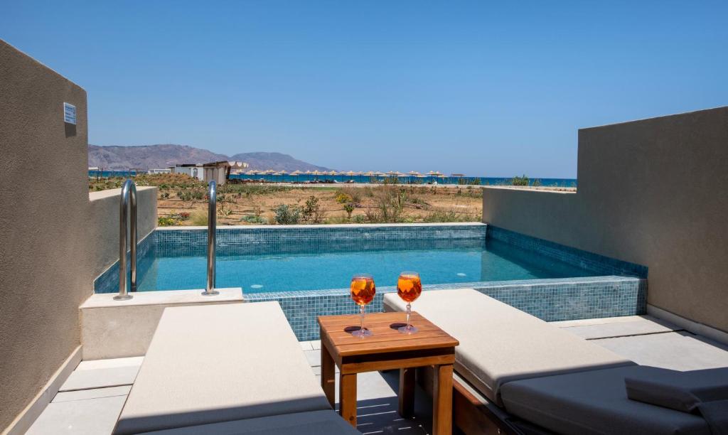 Privātā baseina zona ar skatu uz jūru, divi sauļošanās krēsli un kokteiļi uz galda. Ideāla vieta atpūtai un relaksācijai.