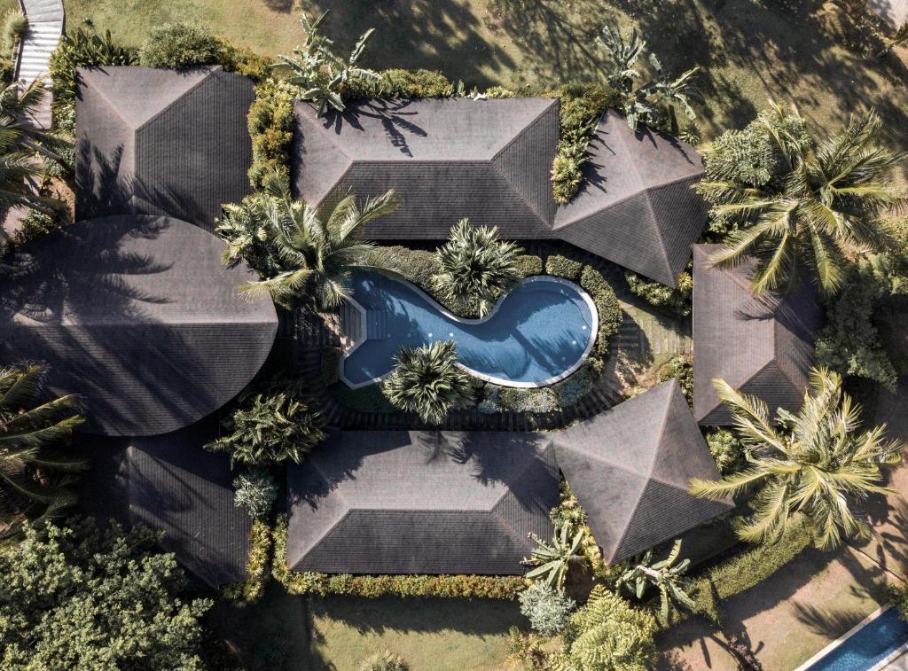 Mūsdienīga kūrorta kompleksa gaisa skats ar baseinu un tropisko veģetāciju. Eleganti jumti un zaļumi rada mierīgu atmosfēru.