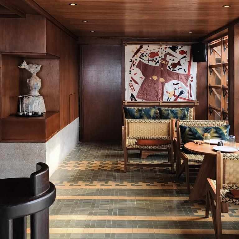 Mūsdienīga kafejnīca ar siltu koka apdari, stilīgu mēbelēm un māksliniecisku sienas gleznojumu, radot patīkamu un viesmīlīgu atmosfēru.