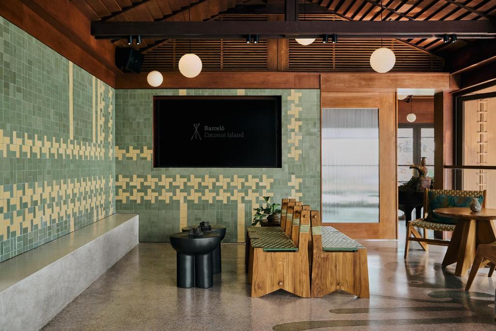 Mūsdienīga interjera telpa ar zaļiem un dzelteniem flīzēm, koka mēbelēm un gaismas ķermeņiem, radot viesmīlīgu atmosfēru. Ideāli piemērota relaksācijai un socializēšanai.