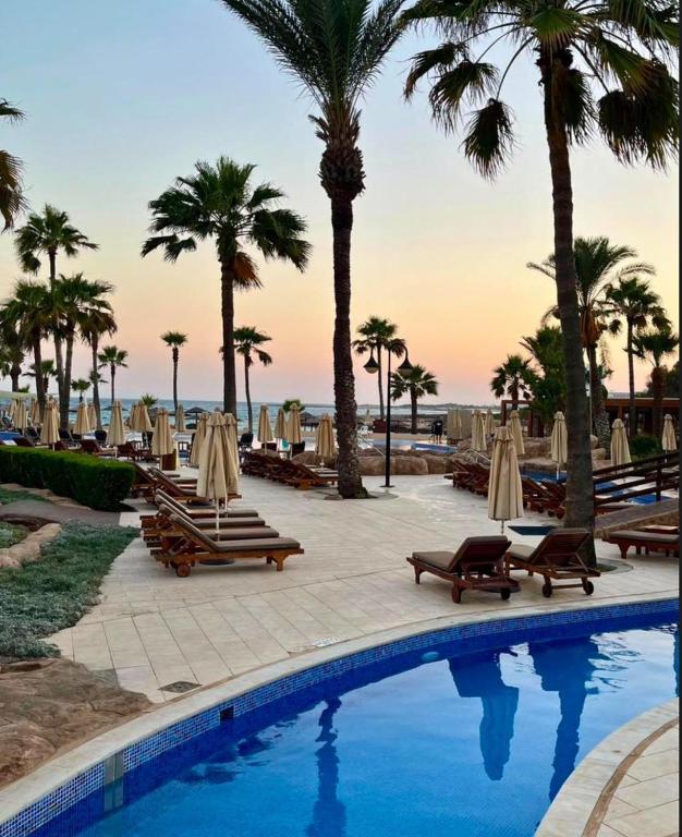 Adams Beach baseins ar palmām saulrietā