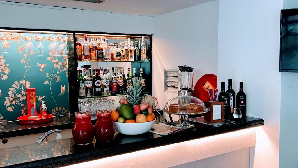 Bārs ar plašu dzērienu izvēli, augļiem un kūkām, ar stilīgu dizainu un zaļu ziedu tapeti. Ideāla vieta relaksācijai un izklaidei.