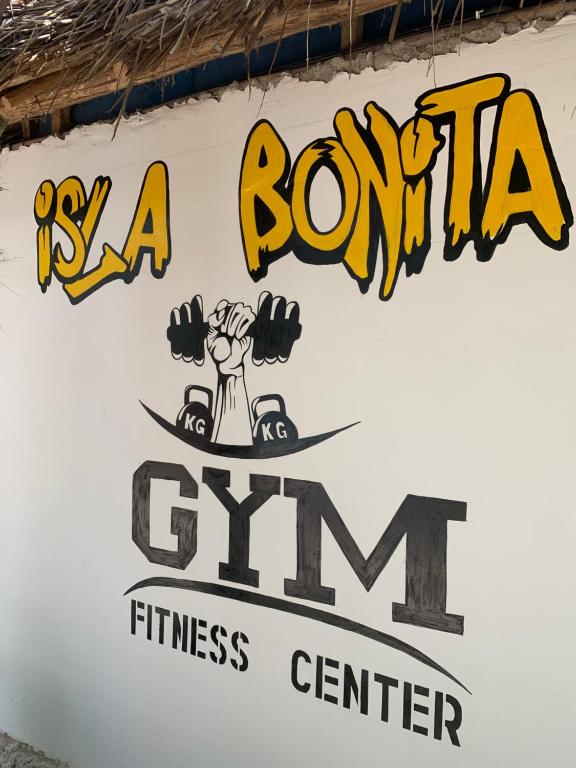 Sienas gleznojums ar nosaukumu "Isla Bonita", kas ietver svaru pacelšanas simboliku un "GYM FITNESS CENTER" nosaukumu.