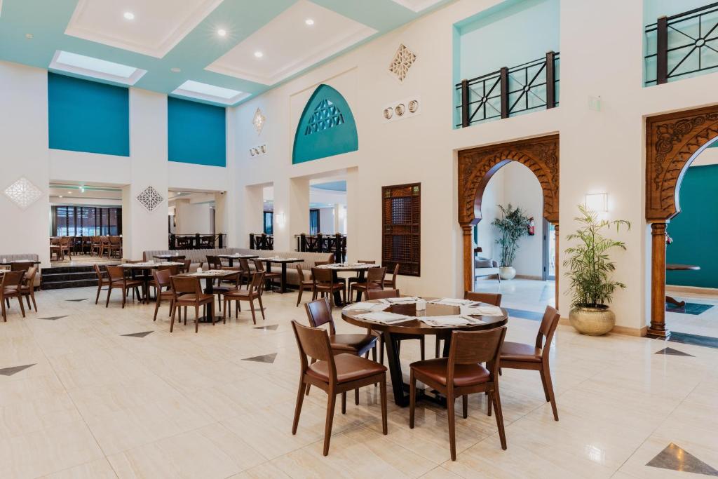 Moderns restorāns ar elegantiem galdiem un krēsliem, dekorēts ar teal krāsas akcentiem un ar arhitektūras elementiem, kas piešķir telpai unikālu šarmu.