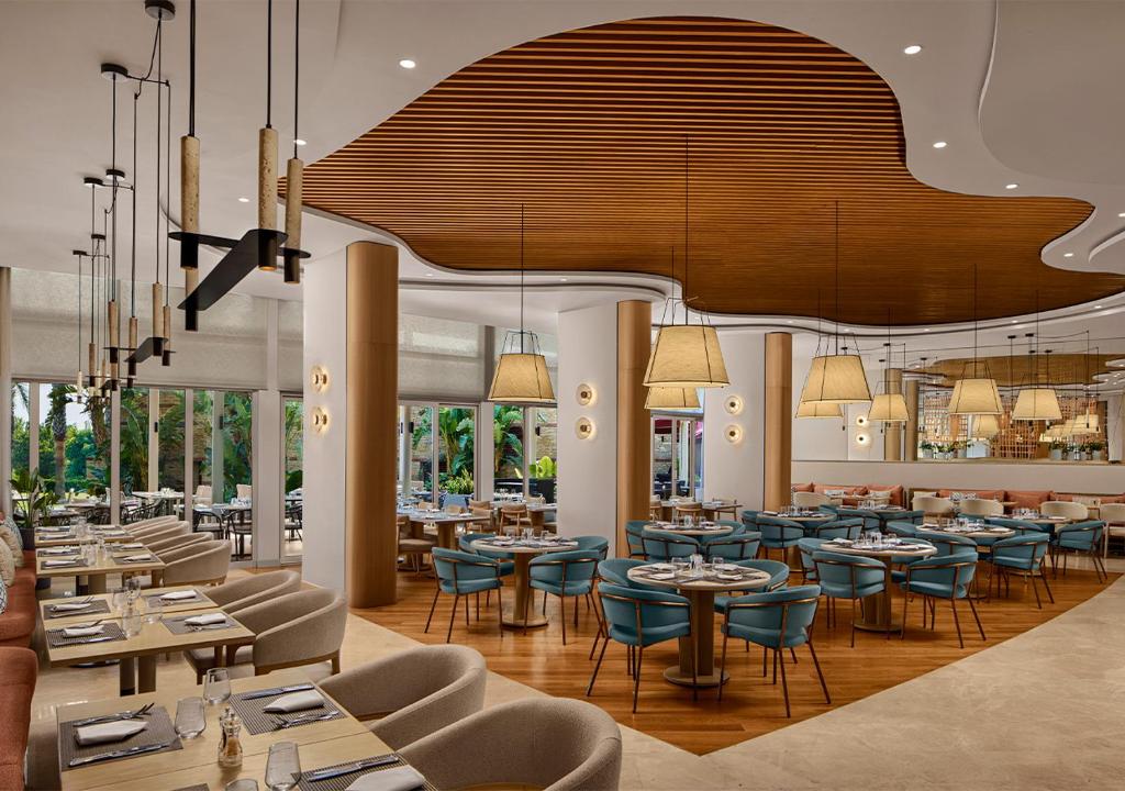 Moderns restorāns Akra Sorgun Tui Blue Sensatori ar elegantiem galdiem un apgaismojumu.