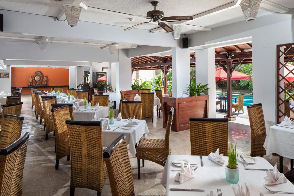 Restorāns Prime Plaza Hotel Sanur ar elegantiem galdiem un dabas elementiem.