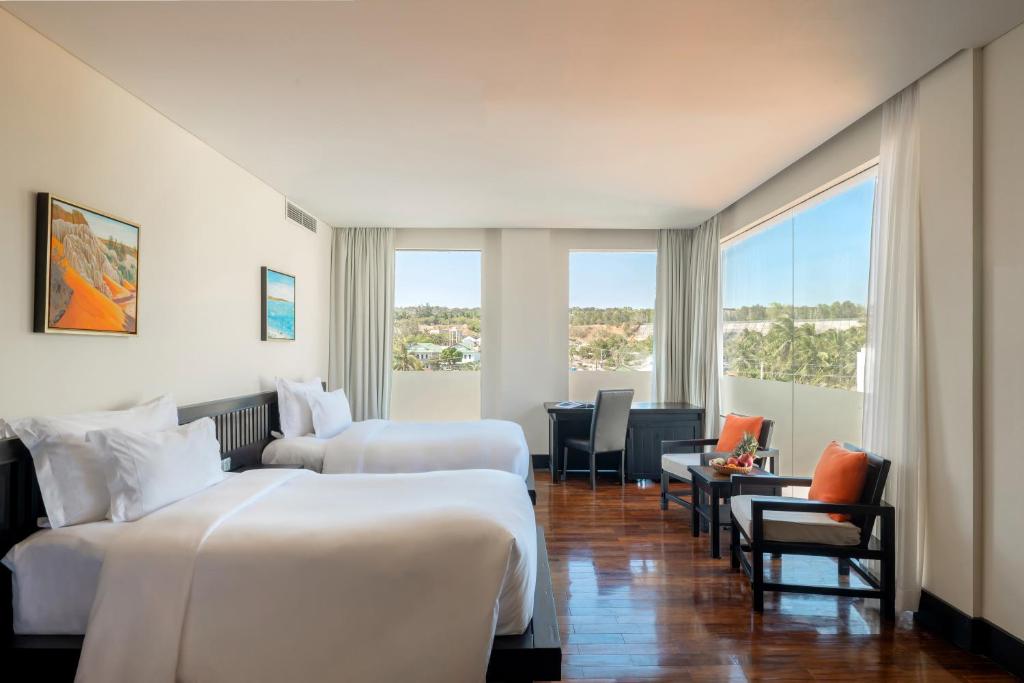 Mūsdienīga viesnīcas istaba ar divām gultām, darba stūrīti un plašiem logiem, caur kuriem redzama ainava. Interjeru papildina mākslas darbi uz sienām un ērtas mēbeles.