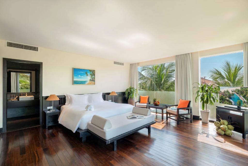 Mūsdienīgs viesnīcas numurs ar plašu gultu, dabisko apgaismojumu un skatu uz palmām. Interjerā ir eleganti mēbeļu elementi un dekoratīvi augi, radot relaksējošu atmosfēru.