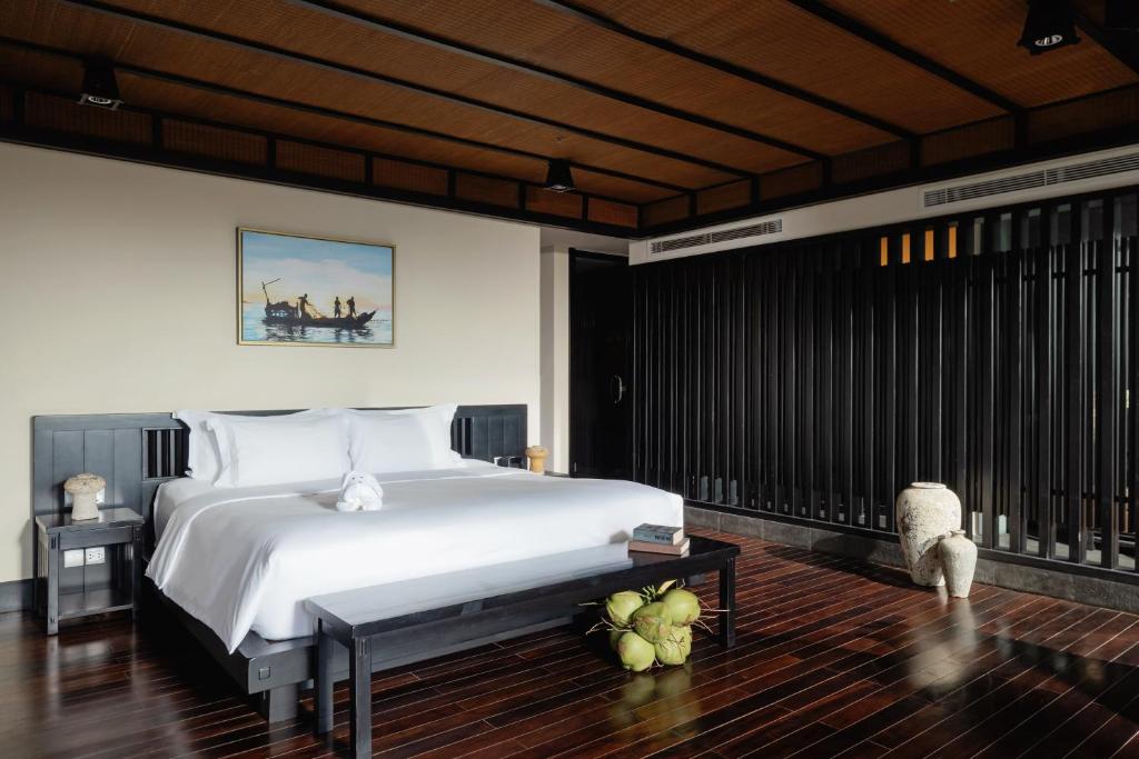 Mūsdienīgs guļamistabas interjers ar gultu, melnu koka mēbelēm un gleznām uz sienām. Telpā ir eleganta apgaismojuma sistēma un siltas krāsas koka grīdas.