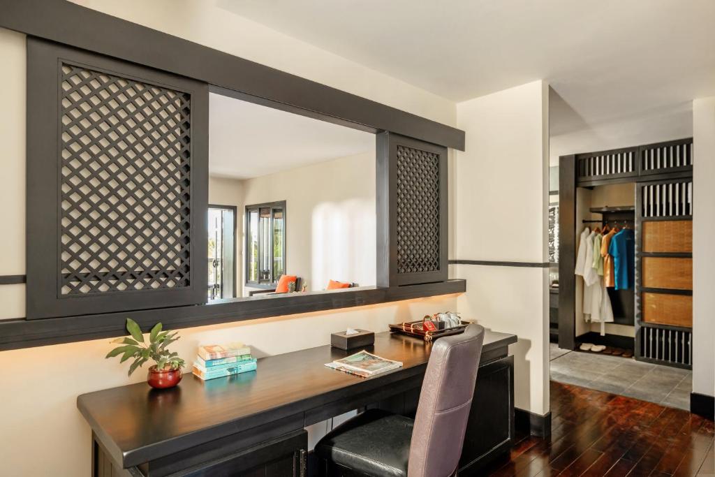 Mūsdienīgs darba stūris ar elegantu melnu rakstu paneļa aizsargu, kas atrodas pie loga, un tuvumā redzama garderobe ar apģērbu. Interjers ir gaišs un gaumīgs, radot komfortablu atmosfēru.