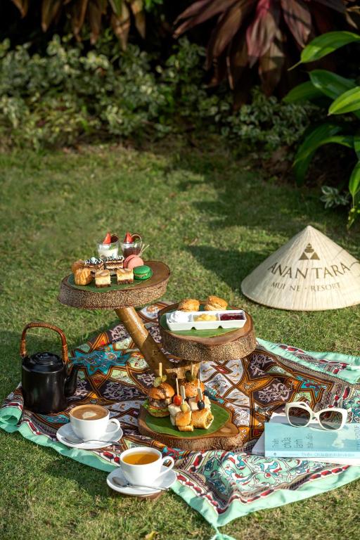 Elegantā kafijas un uzkodu servēšana ārā uz greznas paklāja ar garšīgām delikatesēm un dzērieniem, kas papildina relaksējošo atmosfēru.