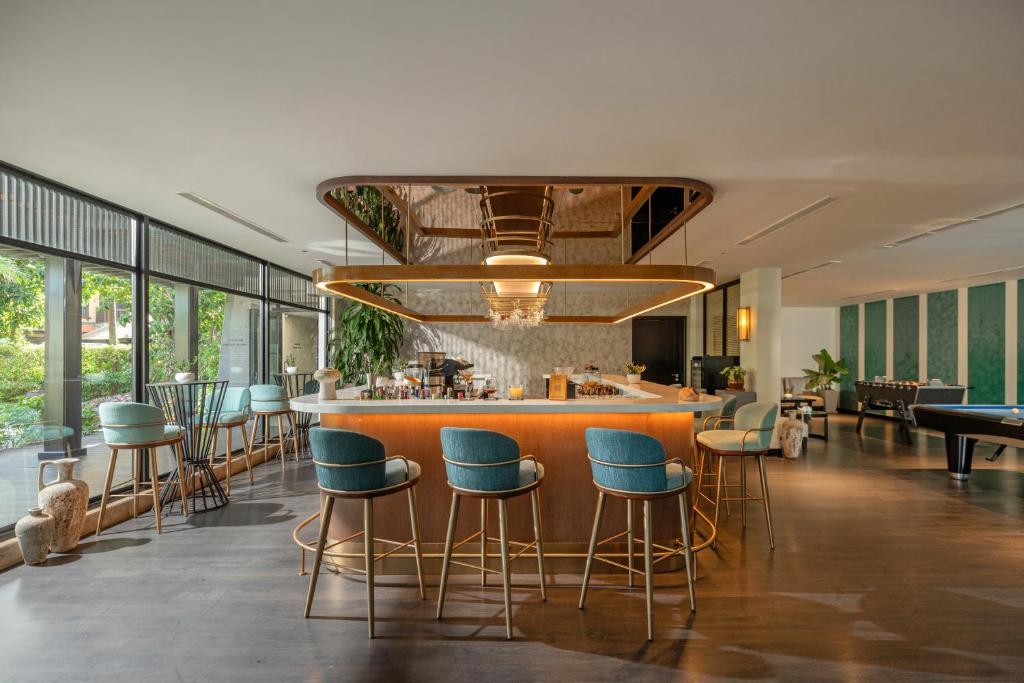 Moderns bārs ar elegantu interjeru, kurā ir stilīgas krēsli un plaši logi, kas nodrošina dabisko apgaismojumu. Apskatāma arī biljarda galda zona un zaļa auga dekorācijas.