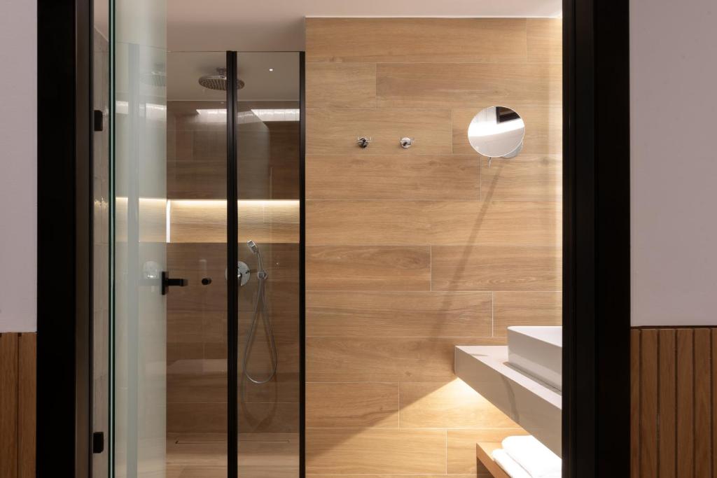 Mūsdienīgs vannas istabas interjers ar stikla dušu un koka apdari. Svaiga un minimālisma estētika, kas ietver modernu apgaismojumu.