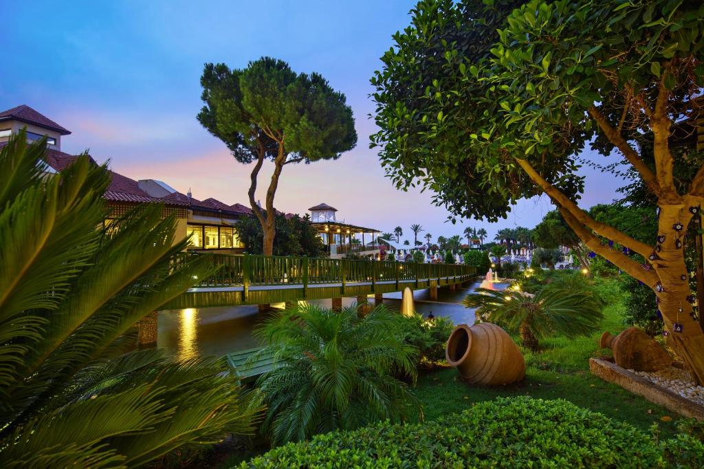 Dārzs ar tiltu pie Bellis Deluxe Hotel piekrastē saulainā vakarā.