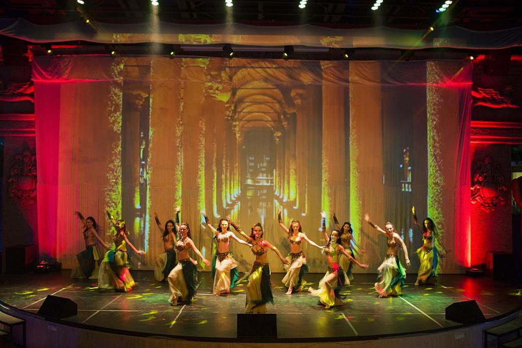 Dejotājas uz skatuves Bellis Deluxe Hotel, krāsains fons.