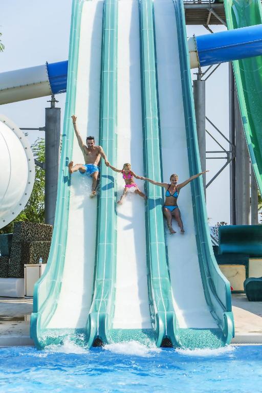 Bērni un pieaugušie slidinās no ūdens slidkalniņiem Bellis Deluxe Hotel.