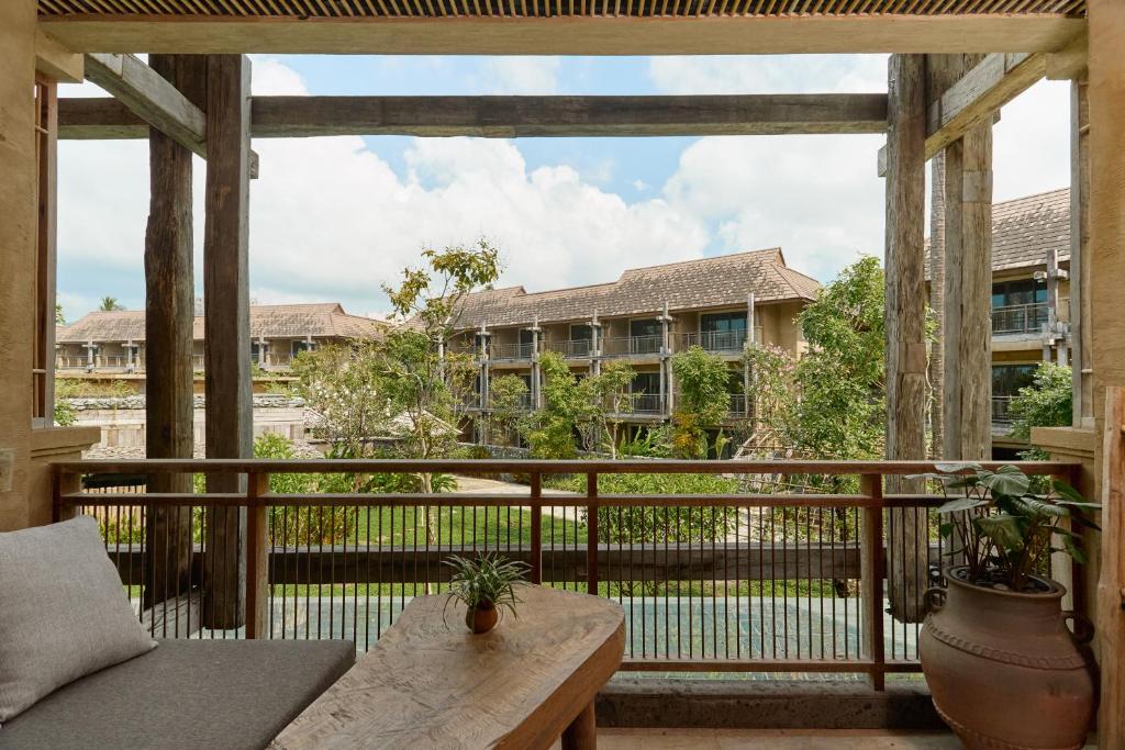 Mūsdienīga viesnīcas balkona ainava ar skatu uz dārzu un arhitektūru, kas apvieno dabiskos materiālus un mūsdienu dizainu. Ideāla vieta relaksācijai un dabas baudīšanai.