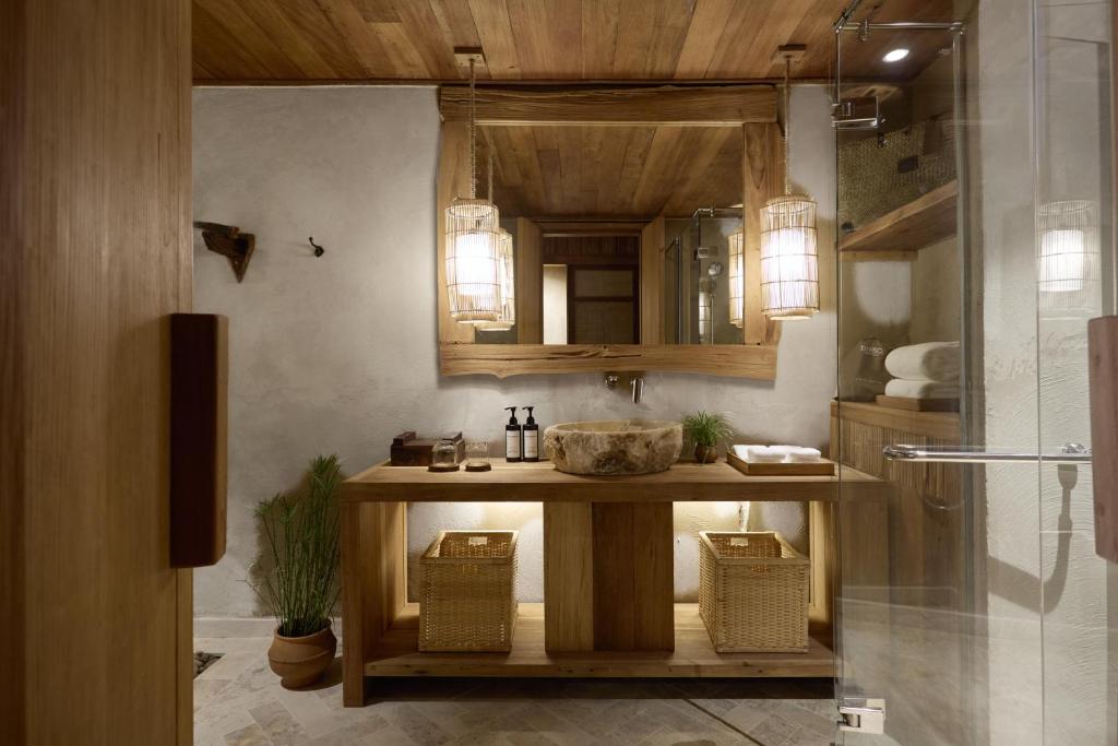 Mūsdienīgs vannas istabas interjers ar koka apdari, akmens izlietni un siltu apgaismojumu, radot relaksējošu atmosfēru. Iekārtota ar dabīgiem elementiem un stilīgiem glabāšanas risinājumiem.