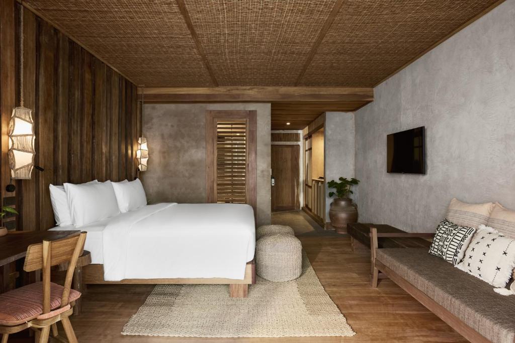 Mūsdienīga viesnīcas istaba ar koka apdari, divguļamo gultu un ērtu atpūtas zonu. Interjers ietver dabīgus materiālus un siltas krāsas, radot relaksējošu atmosfēru.