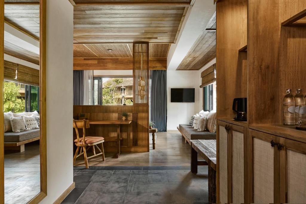 Mūsdienīga viesnīcas numura interjers ar koka akcentiem, ērtu sēdvietu un lieliem logiem, kas nodrošina dabīgu apgaismojumu. Svaiga un relaksējoša atmosfēra.