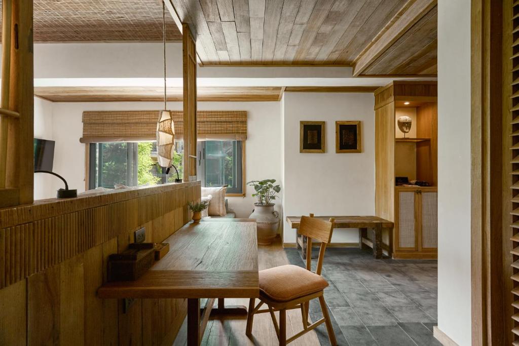 Mūsdienīga interjera telpa ar dabīgu koka apdari, ērtu galdu un krēslu, kā arī logiem, kas nodrošina dabisko apgaismojumu. Telpā ir redzami dekoratīvi elementi un relaksējoša atmosfēra.