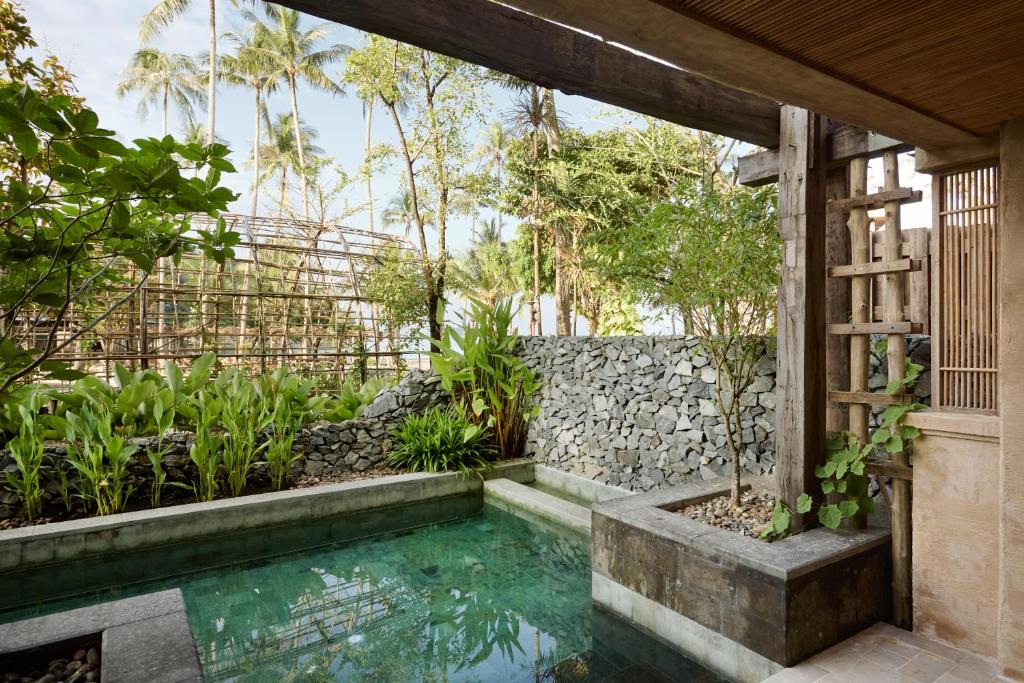 Tropu dārzs ar baseinu un zaļumiem, apņemts ar akmens sienu un koka konstrukciju. Ideāla vieta relaksācijai un harmonijai ar dabu.