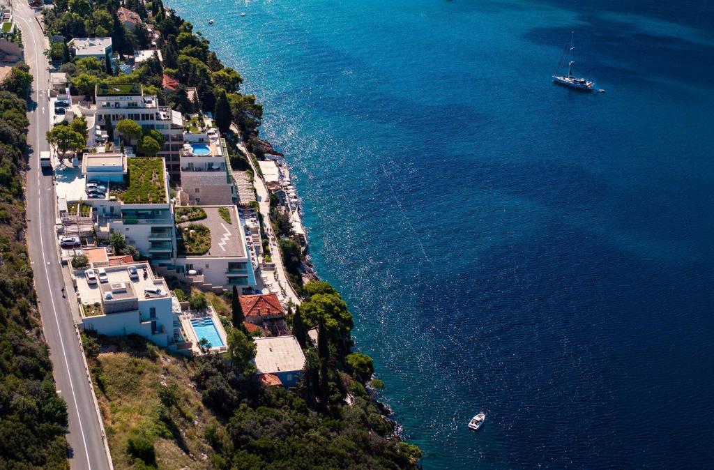 Apskatāms piekrastes skats ar modernām ēkām, baseiniem un laivu, kas plūdina mierīgajos ūdeņos. Gaismas atspīdums ūdenī radītais burvīgs atmosfēra.