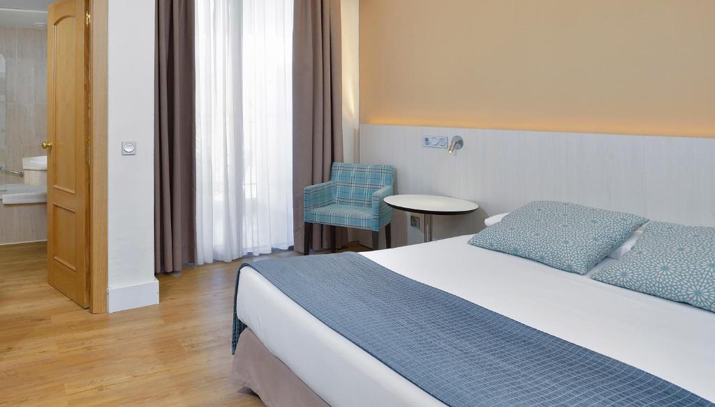 Mūsdienīgs viesnīcas numurs ar gaisīgu interjeru, koka grīdu un ērtu gultu. Telpā ir gaiši aizkari un atpūtas krēsls, kas nodrošina komfortu un relaksāciju.