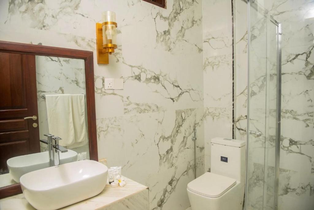 Mūsdienīgs vannas istabas interjers ar marmora apdari hotelī AHG Hisia Nungwi Experience.