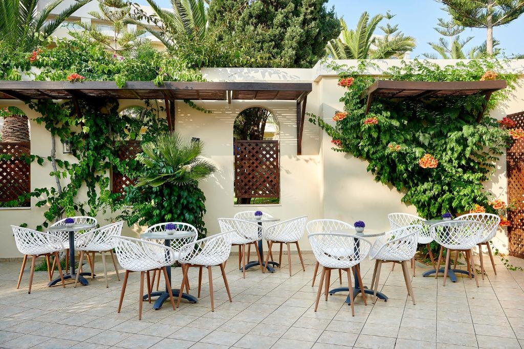 Terases zona ar baltiem krēsliem un zaļumiem pie Iberostar Waves Creta Panorama & Mare.