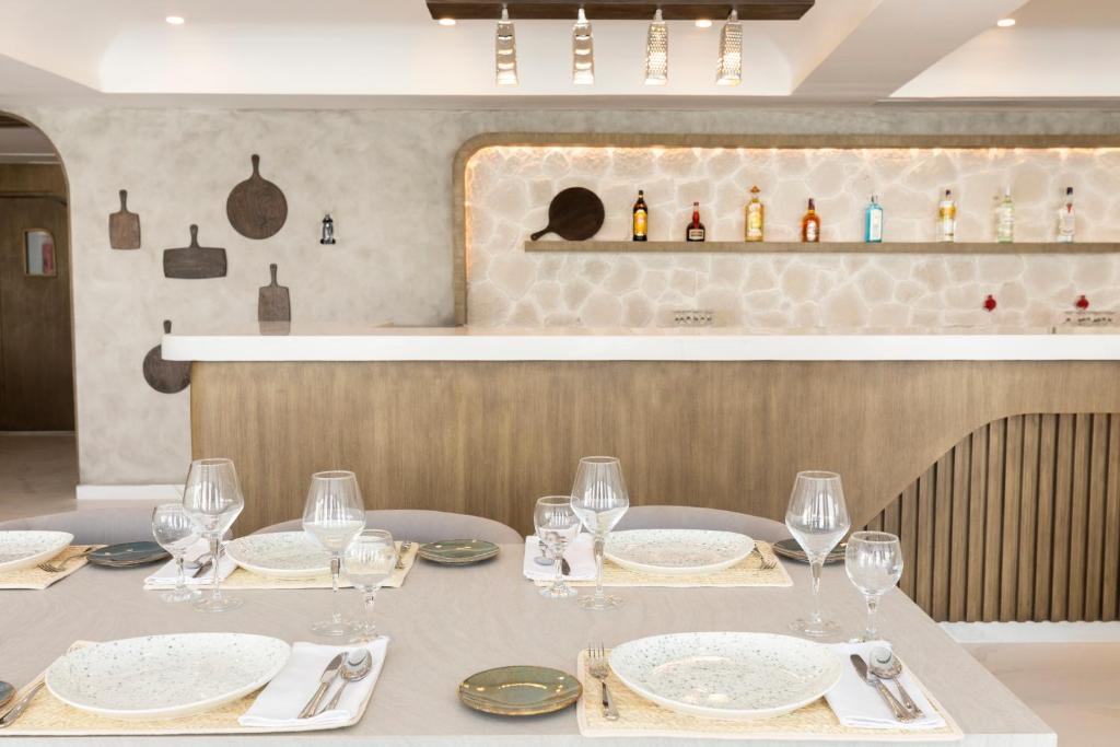 Mūsdienīgs restorāna interjers ar eleganti klātu galdu, dekorētu ar porcelāna traukiem un glāzēm, fona sienas ar koka akcentiem un elegantu bāru.