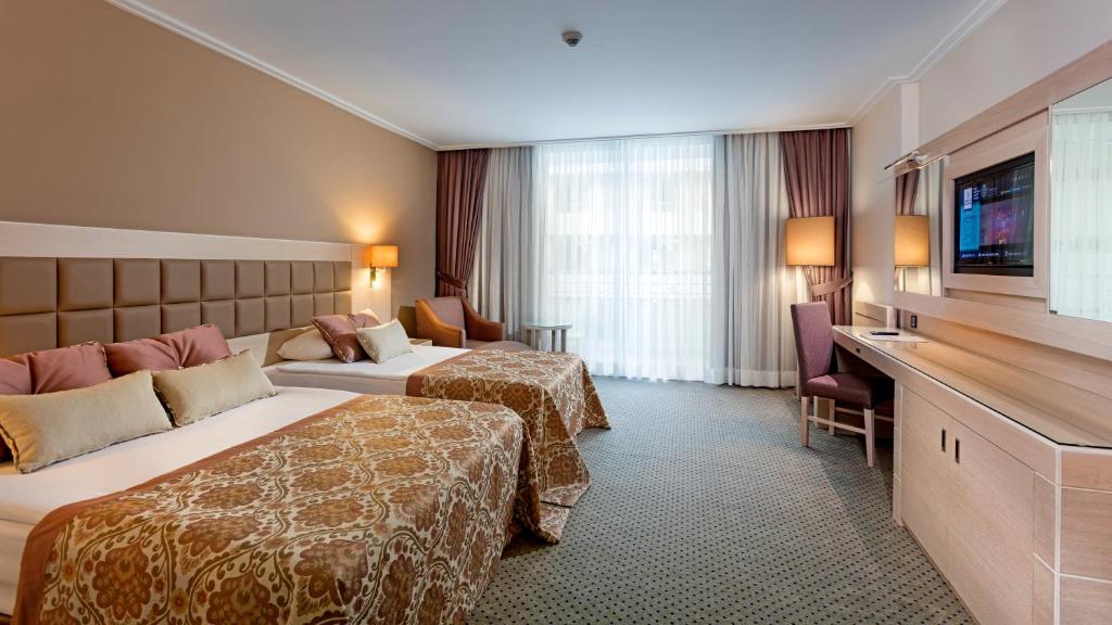 Mūsdienīgs numurs Miracle Resort Hotel ar divām gultām un televizoru.