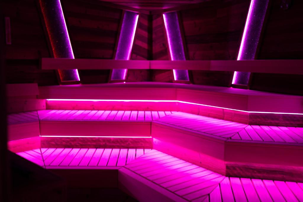 Modernā pirts ar rozā LED apgaismojumu, kas rada relaksējošu un mājīgu atmosfēru. Koka sēdvietas un apgaismojums piešķir stilīgu izskatu.