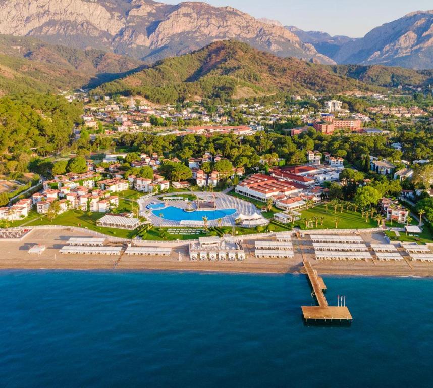 Skats no gaisa uz Club Marco Polo viesnīcu piekrastē ar baseinu un kalniem fona. panoramic view with beach and pools