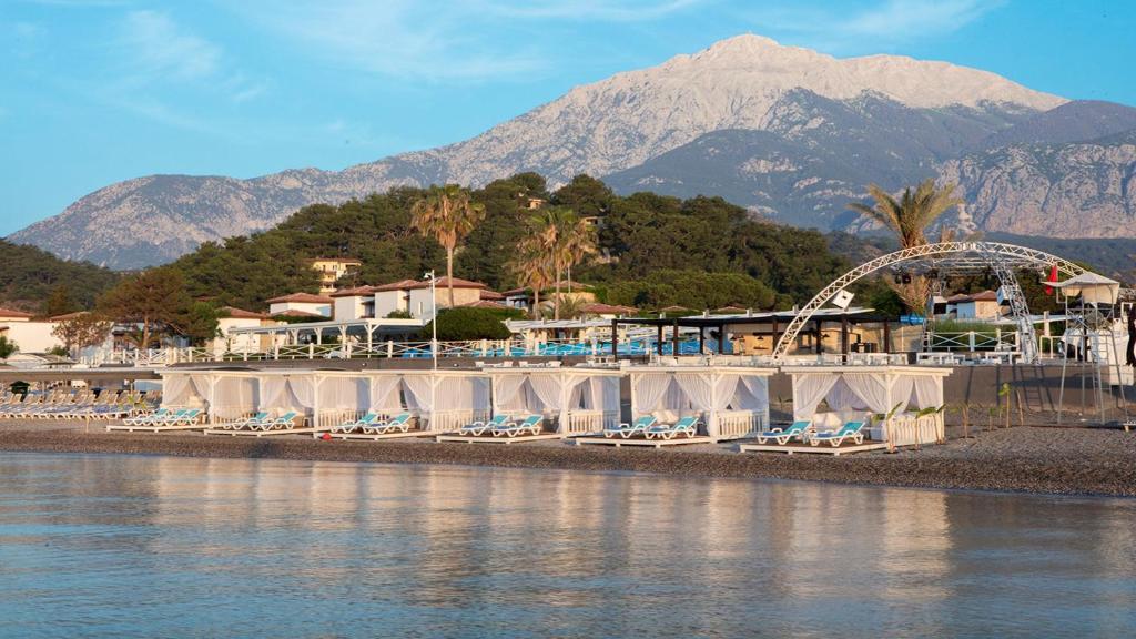 Viesnīca Club Marco Polo piekrastē ar kabīnēm un kalniem fona.
