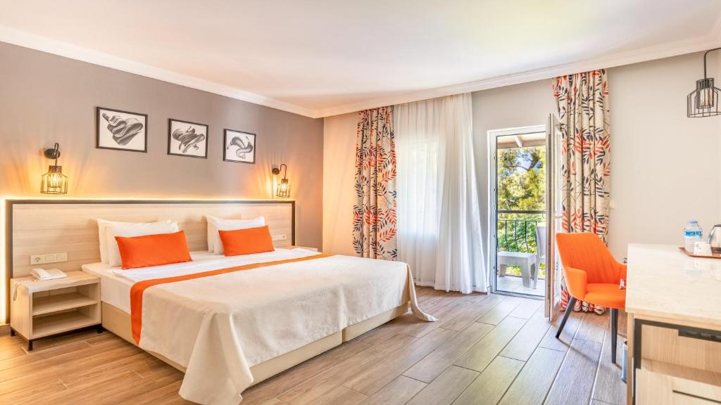 Mūsdienīgs numurs viesnīcā Club Marco Polo ar balkonu un oranžiem akcentiem.