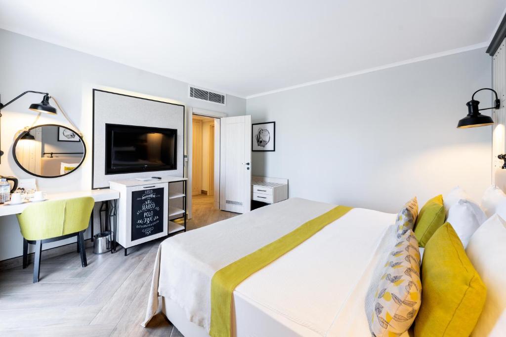 Mūsdienīgs numurs viesnīcā Club Marco Polo ar ērtu gultu un TV.