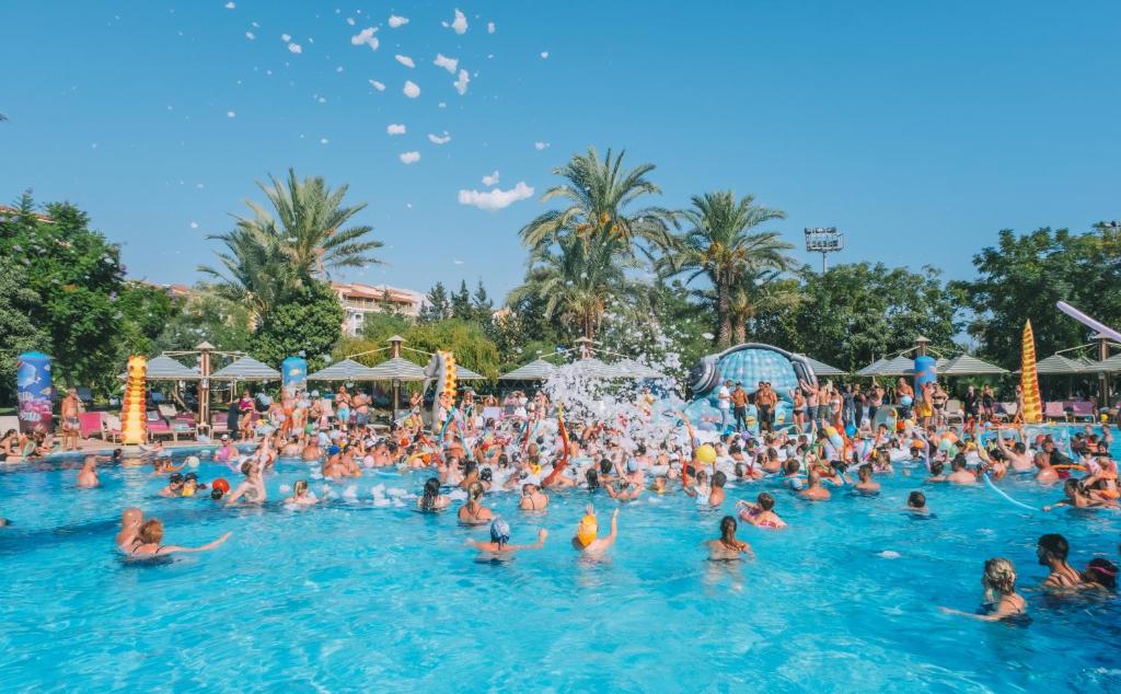 Lieliska izklaide pie Belconti Resort Hotel baseina ar viesiem, kas izbauda ūdens priekus.