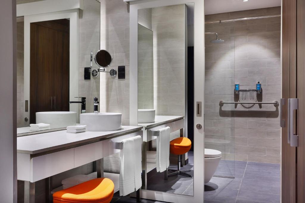 Modernā vannas istaba Aloft Al Mina viesnīcā ar dušu un izlietni.