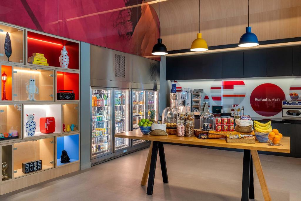 Aloft Al Mina viesnīcas pašapkalpošanās ēdamzāle ar uzkodām un dzērieniem.