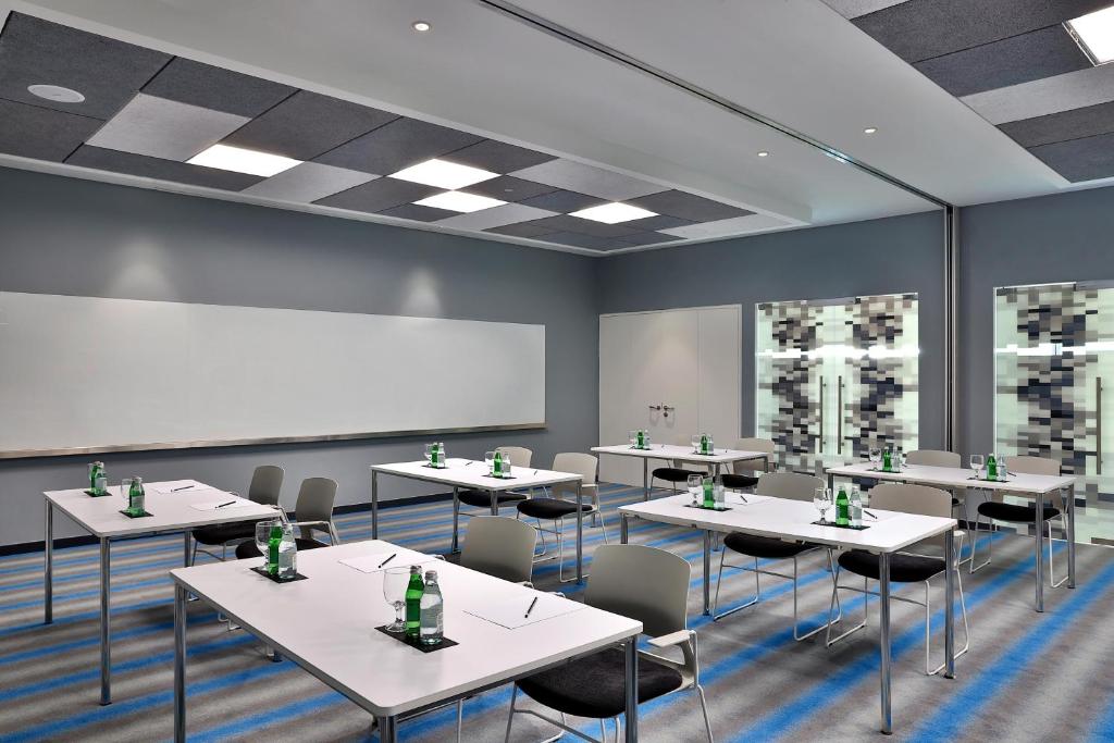 Aloft Al Mina konferenču zāle ar moderniem galdiem un krēsliem
