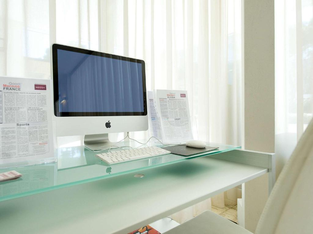 Moderns rakstāmgalda izskats ar Apple datoru, baltiem aizkariem un laikrakstiem. Ideāla vide produktīvai darbībai.